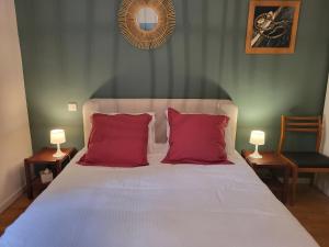 a bedroom with a bed with red pillows and two lamps at Sur le bassin d'Arcachon in Lanton