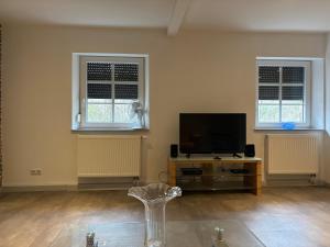 a living room with a flat screen tv and two windows at Salinenappartement in Bad Kreuznach