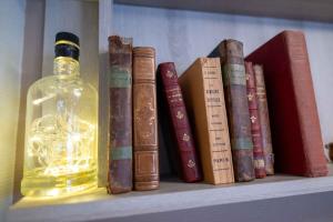 a shelf with a bottle of whiskey and books at Auberge du Cezallier in Montgreleix