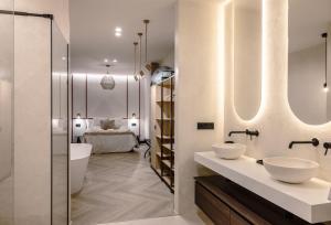 a bathroom with two sinks and a bedroom in the background at Castelar Urban Suites in Badajoz +123 photos