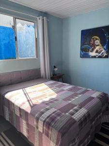 a bedroom with a bed with a plaid blanket and a window at Loft Sousas in Campinas