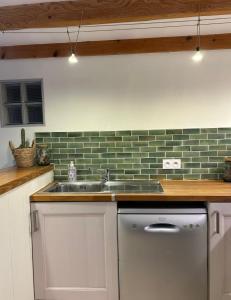 a kitchen with a sink and green subway tiles at La Maison dans les Nuages in Sécheras