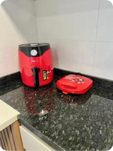 a red toaster sitting on top of a kitchen counter at Suíte completa com cozinha próximo ao mar in Torres