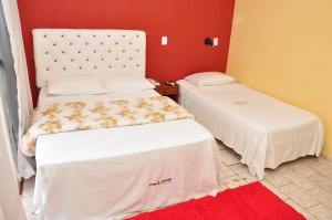 two beds in a room with a red wall at Pirâmide Palace Hotel in Nobres