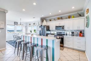 a kitchen with white cabinets and a counter with stools at Gulf Breezes Unit A in Port Aransas