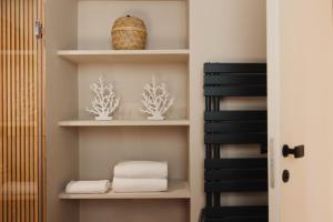 a bathroom with white shelves with towels and a basket at CŌRA Ortigia in Syracuse +87 photos