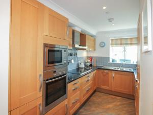 a kitchen with wooden cabinets and stainless steel appliances at 16 Bolt Head in Salcombe