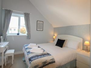 a bedroom with a bed and a desk and a window at 16 Bolt Head in Salcombe