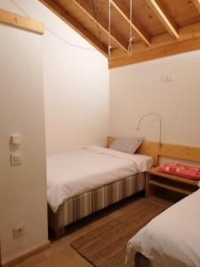 two beds in a room with white walls and wooden ceilings at Sorte do Jugo - Lakeside cottage with private beach in Vieira do Minho