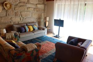 a living room with two couches and a stone wall at Sorte do Jugo - Lakeside cottage with private beach in Vieira do Minho
