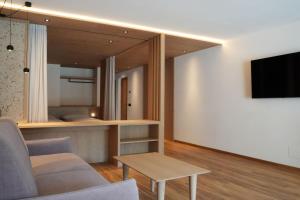 a living room with a couch and a tv on a wall at Runk Apartments in Siusi