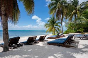 a row of lounge chairs on a beach with the ocean at Villa Angela in Isla Mujeres