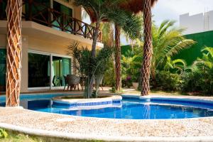 a swimming pool in front of a house with palm trees at Villa Angela in Isla Mujeres
