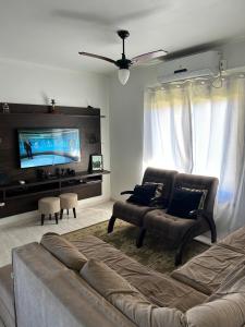 a living room with a couch and a flat screen tv at Pedra Branca Retreat in Garopaba