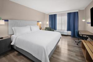 a hotel room with a large white bed and a desk at Garner Hotel Lincoln North by IHG in Lincoln