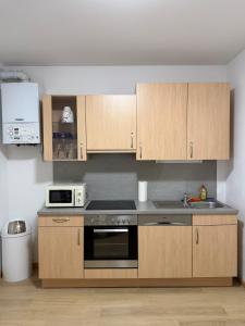 a kitchen with wooden cabinets and a microwave at Moderne zentrale Wohnung in Grosspetersdorf