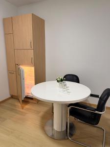 a white table and two black chairs in a room at Moderne zentrale Wohnung in Grosspetersdorf