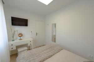 a white bedroom with a bed and a desk at Casa Estação Douro Vista in Vila Marim