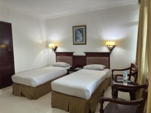 a hotel room with two beds and a table and chair at PIA Hotel Bandung in Bandung