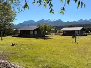 two buildings in a field with mountains in the background at Lodge Ruta 71 in Trevelín