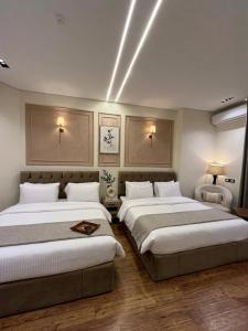two beds in a hotel room with two lamps at New LH Cairo Hotel in Cairo