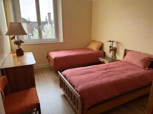 a room with two beds and a chair and a window at TOUCY Vintage in Toucy
