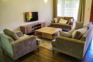 a living room with two couches and a tv at Pacificas place in Eldoret