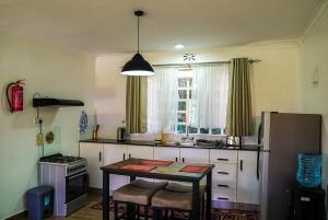 a kitchen with a table and a refrigerator and a window at Pacificas place in Eldoret