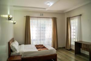 a bedroom with a bed and a large window at Pacificas place in Eldoret