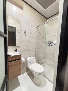 a white bathroom with a toilet and a shower at Aparta Hotel La Osadía in Acacías