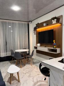a living room with a tv and tables and chairs at Aparta Hotel La Osadía in Acacías +18 photos