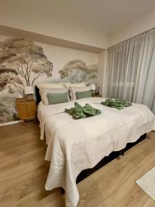 a bedroom with a large white bed with green leaves on it at HelloWine Apartman II in Eger