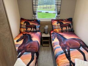 two beds with horses on them in a room at West Lawn 47 Haggerston Castle Paddock Views in Berwick-Upon-Tweed