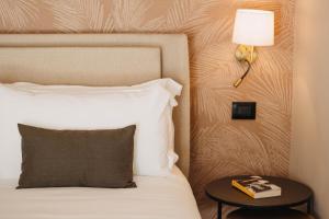 a bed with a lamp and a table with a pillow at CŌRA Ortigia in Syracuse