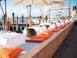 a row of tables and chairs with orange cushions at Stravedo SUNSET in Pellestrina