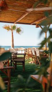 a group of tables and chairs with a palm tree at Indigo Seaside Experience in Adelianos Kampos