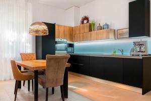 a kitchen with a wooden table and chairs in a kitchen at Luksuzni apartmaji v centru Portoroža z vrtom in parkiriščem - Luxury Apartments in Portoroz Center with Garden & Parking in Portorož