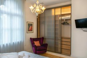 a bedroom with a bed and a chair and a chandelier at Luksuzni apartmaji v centru Portoroža z vrtom in parkiriščem - Luxury Apartments in Portoroz Center with Garden & Parking in Portorož