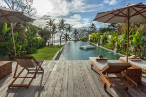 a wooden deck with two chairs and a swimming pool at Private beach Oceanfront 3bd Villa in Cemagi