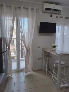 a kitchen with white curtains and a table and a window at Studio Panos 2 in Mytilene