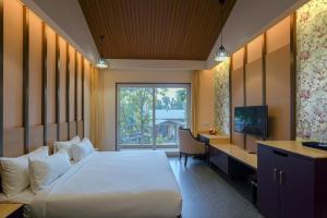 a bedroom with a bed and a desk and a television at Vanasya Retreat Corbett in Amgarhi