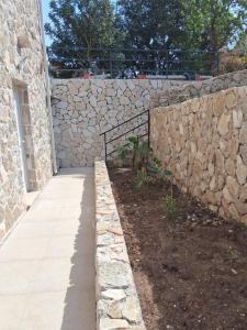 a stone retaining wall next to a walkway at Apartman Lasko in Goveđari