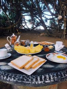 a table with plates of food and bread and fruit at Jasmin Garden in Kalutara