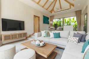 a living room with a white couch and a tv at Trichada Essence in Ban Pak Lak