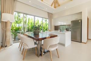 a kitchen with a wooden table and white chairs at Trichada Essence in Ban Pak Lak