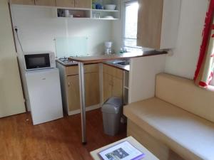 a small kitchen with a refrigerator and a microwave at Camping 3 étoiles - ccbfgdc in Neuvic +7 photos