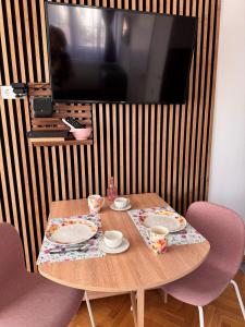 a wooden table with two chairs and a tv at Bérc Apartman in Egerszalók