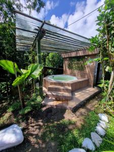 a hot tub in a backyard with a pergola at Mindo Green House in Mindo