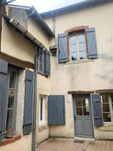 a building with blue shuttered windows and a door at Le Caillou in Reuilly