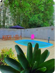 a pool with chairs and an umbrella in a yard at Casa completa com lareira, piscina compartilhada in Torres